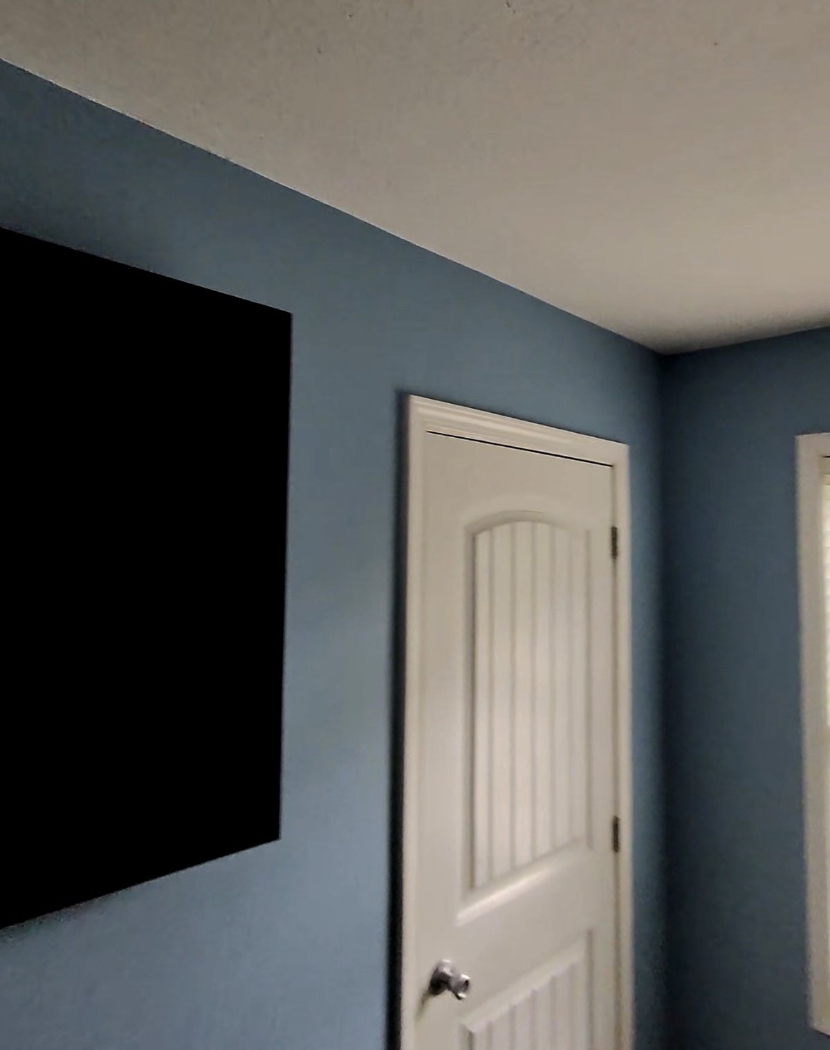 Finished bedroom painted in soft slate blue Emerald Symmetry matte with white trim and door