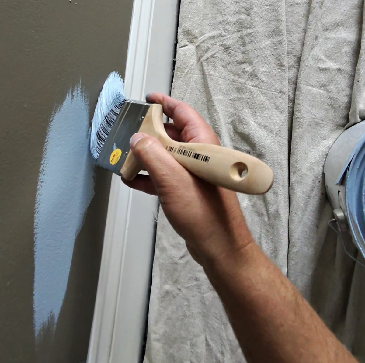 Cutting in soft slate blue Emerald Symmetry paint along white door trim over a taupe wall