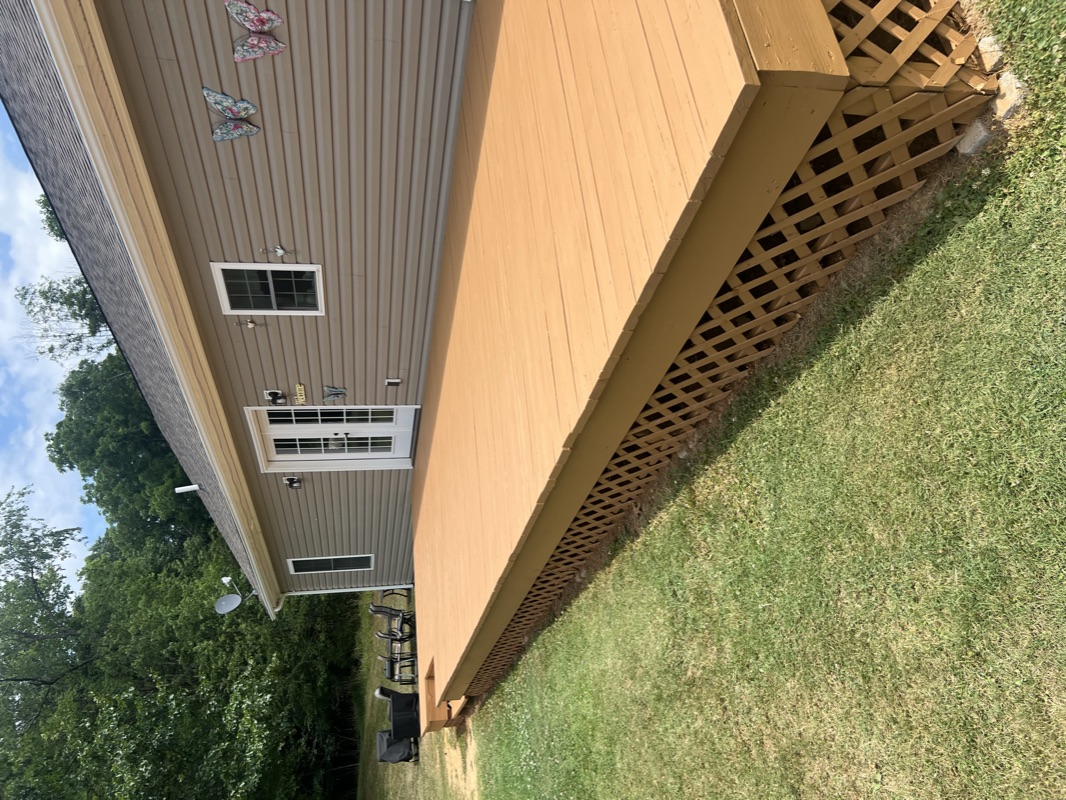 Tan house exterior with freshly stained lattice and deck