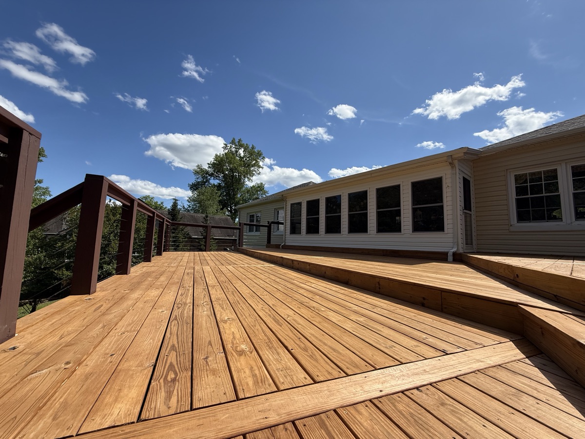 Large deck staining with cable railings and blue sky